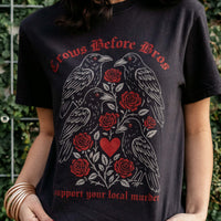 Person wearing a black t-shirt with red and white graphic design of crows and roses, text 'Crows Before Bros' and 'support your local murder'.