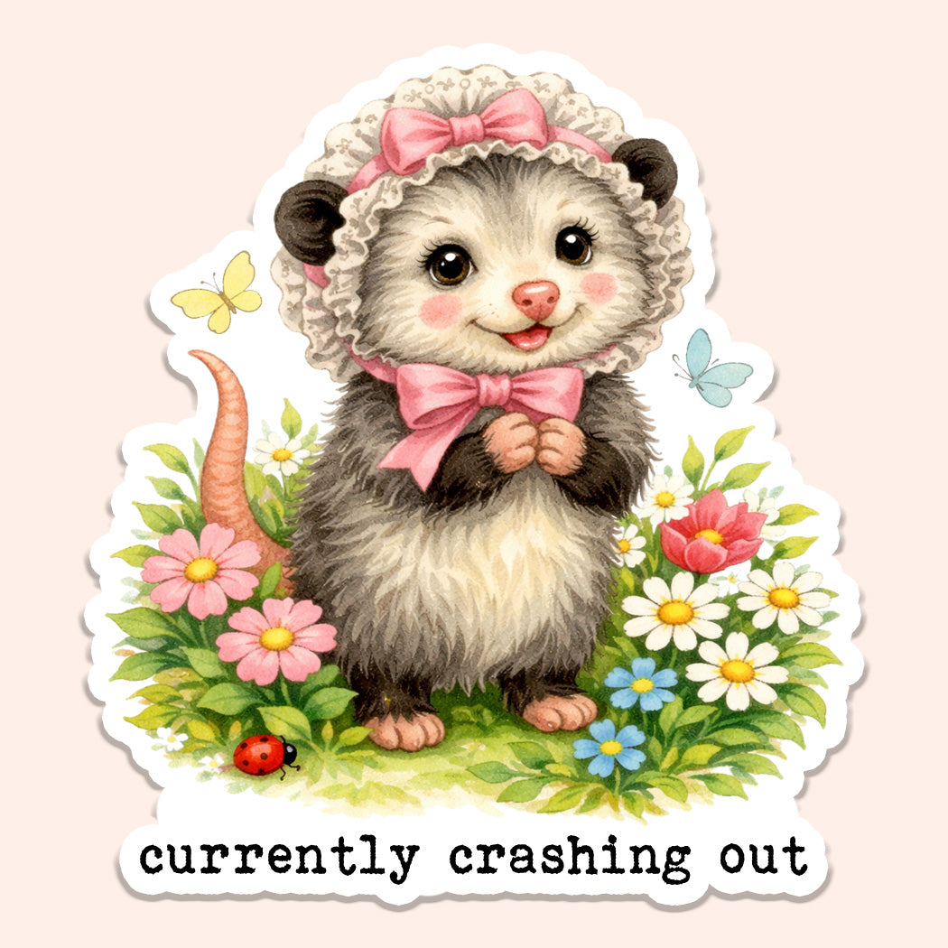 Die-cut vinyl sticker of a cute illustrated opossum wearing a pink bow and frilly bonnet surrounded by flowers with the text "currently crashing out" below