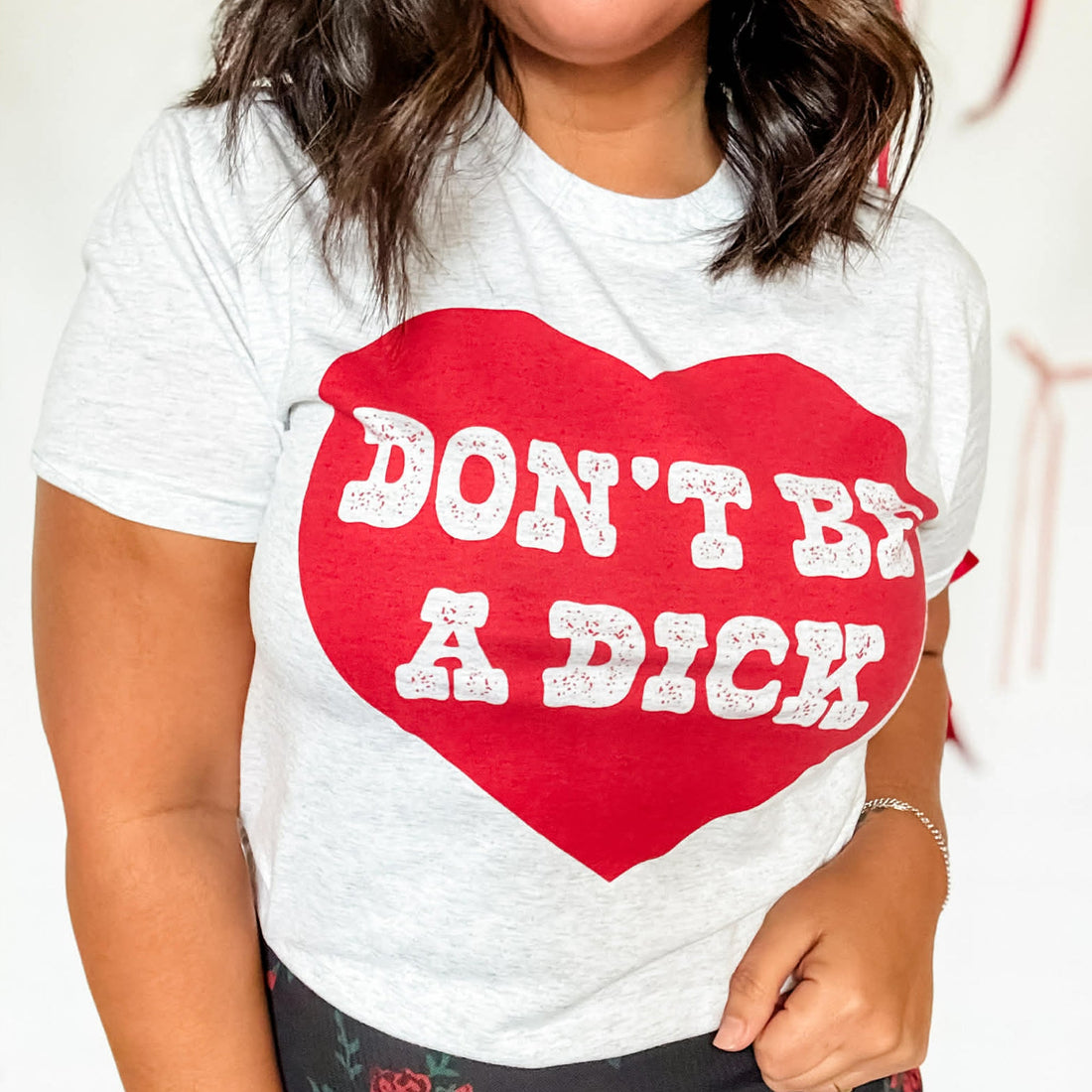 Person wearing a white t-shirt with a red heart and text on a plain background