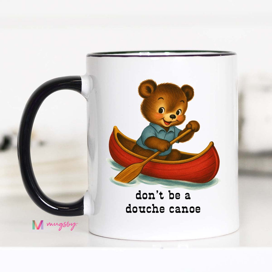 Mug with a bear in a canoe illustration and text 'don't be a douche canoe' on a white background.