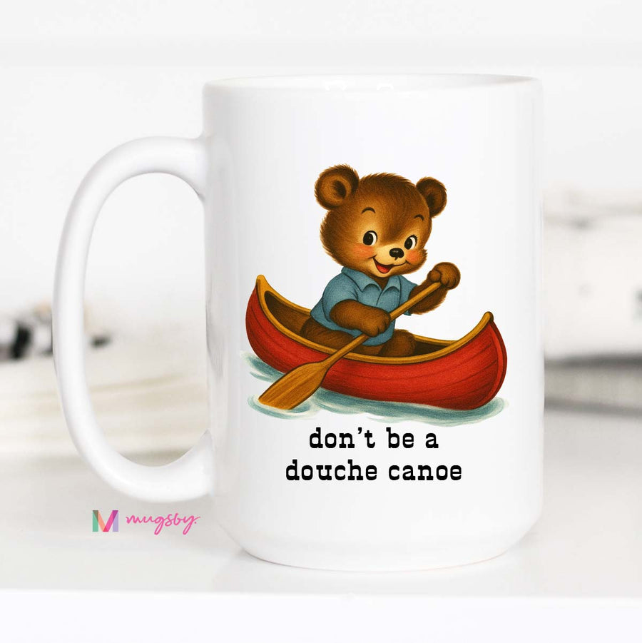 Mug with a bear in a canoe illustration and text 'don't be a douche canoe' on a white background.
