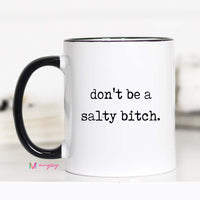 White mug with black interior and handle, featuring the text 'don't be a salty bitch.' on a white background.