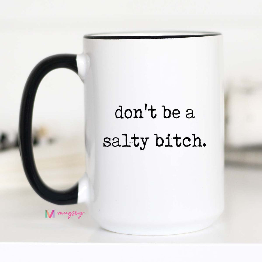 White mug with black handle and text 'don't be a salty bitch' on a white background