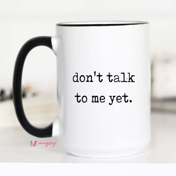 White mug with black handle and text 'don't talk to me yet.' on a white background