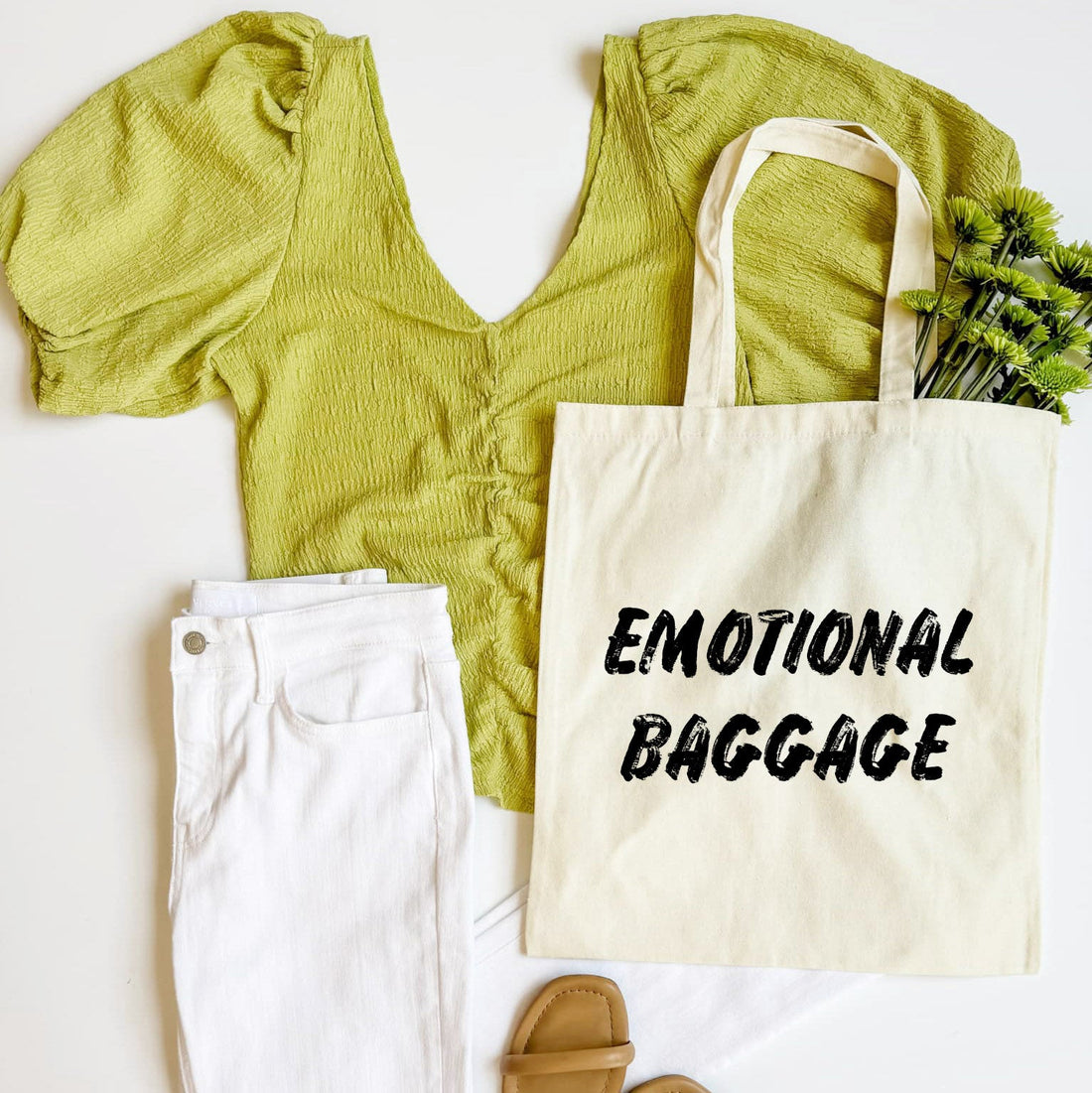 Green top, white pants, beige tote bag with &