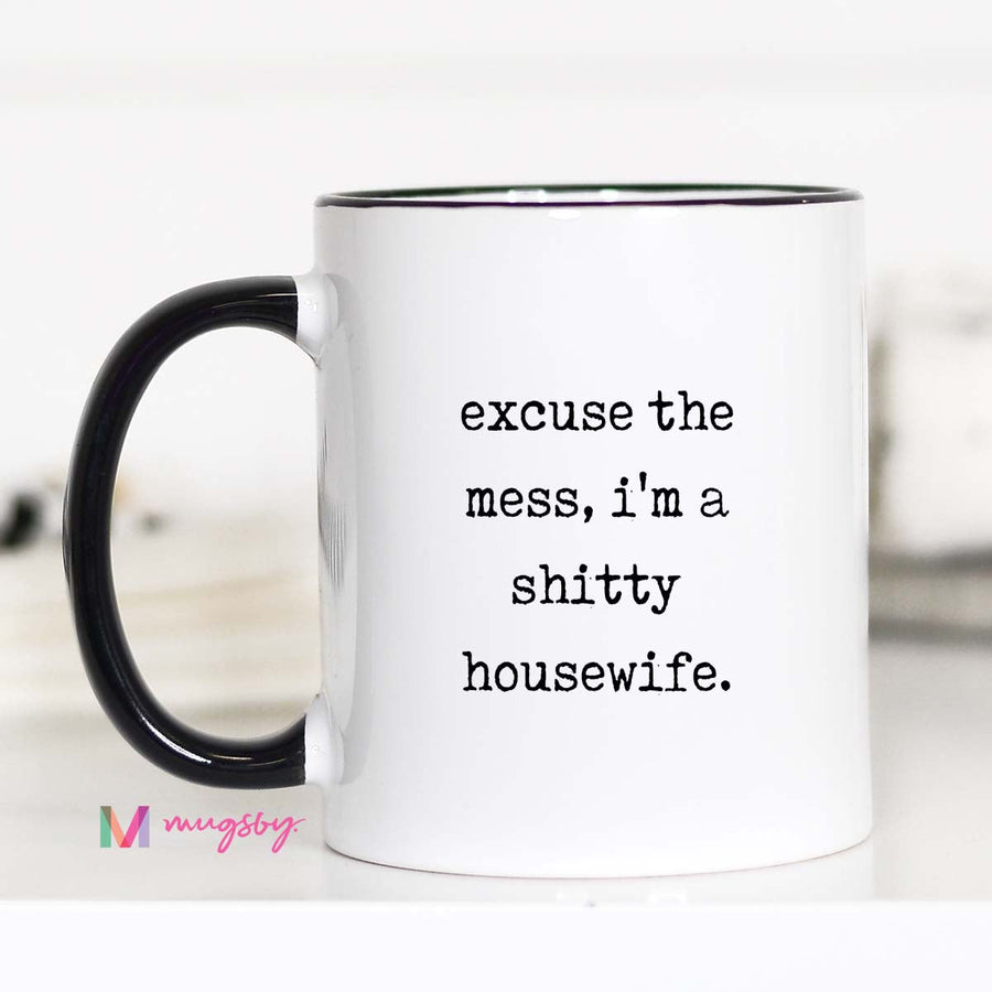 Mug with text 'excuse the mess, i'm a shitty housewife.' on a white background