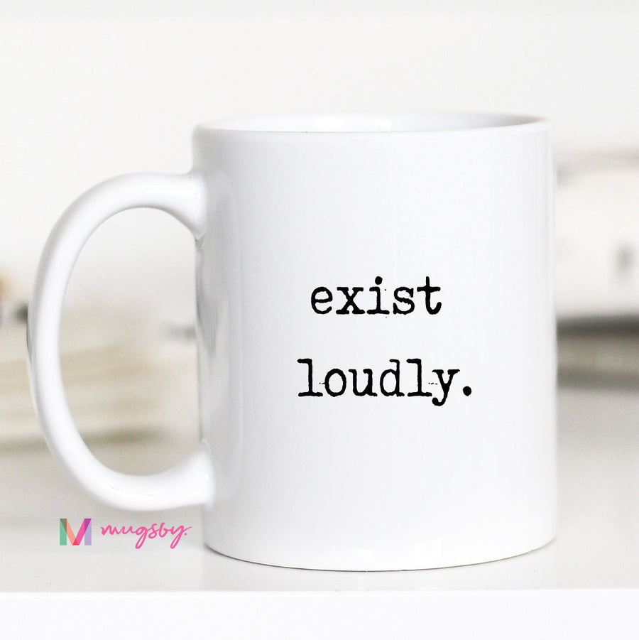White mug with 'exist loudly.' text on a blurred background