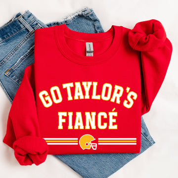 Red sweatshirt with 'GO TAYLOR'S FIANCÙ' text and football helmet graphic on a white background.
