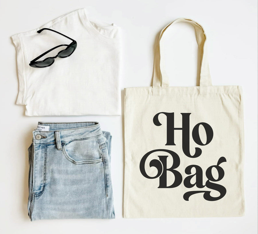 White tank top, blue jeans, black sunglasses, and a tote bag with 'Ho Bag' text on a white background