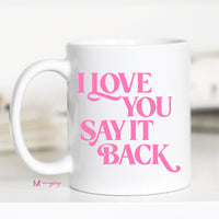 White mug with pink text 'I LOVE YOU SAY IT BACK' on a white background