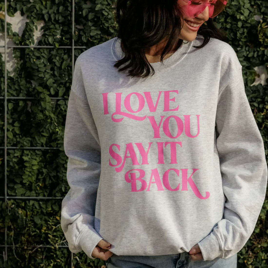 Person wearing a gray sweatshirt with pink text &