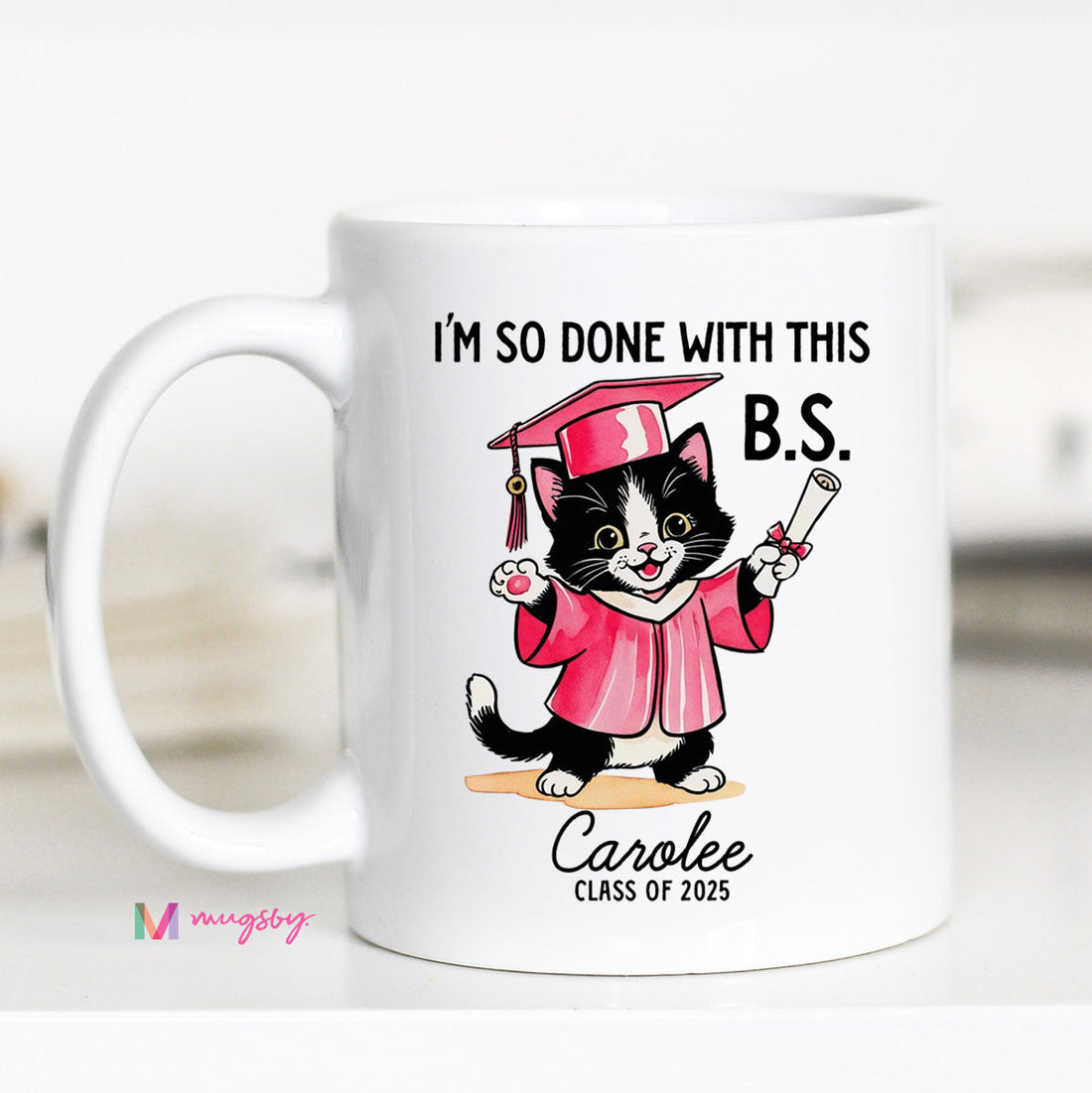A personalized coffee mug with a cartoon image of a cat wearing a graduation cap and gown, holding a diploma, with the text &