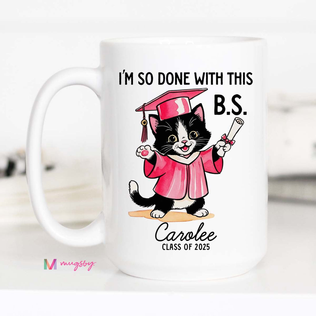A personalized coffee mug with a cartoon image of a cat wearing a graduation cap and gown, holding a diploma, with the text &