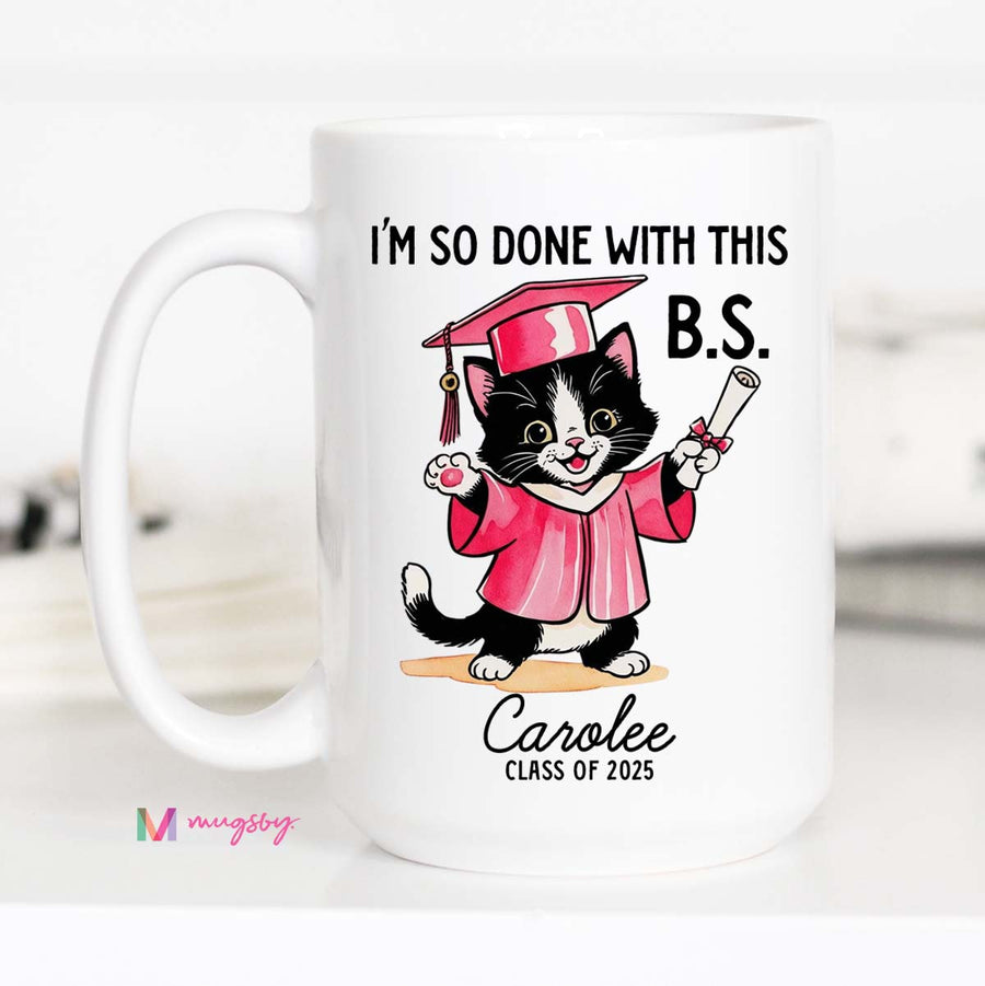 A personalized coffee mug with a cartoon image of a cat wearing a graduation cap and gown, holding a diploma, with the text 'I'M SO DONE WITH THIS B.S.