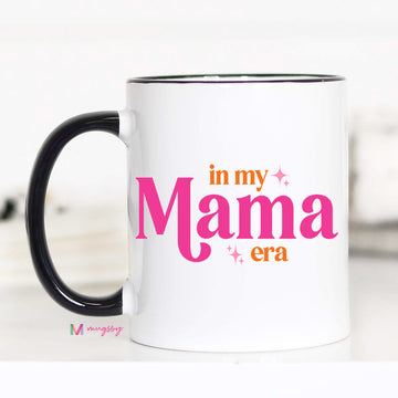 White mug with 'in my Mama era' text in pink and orange on a white background