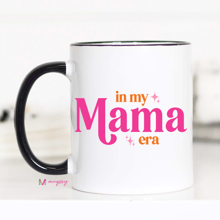 White mug with 'in my Mama era' text in pink and orange on a white background