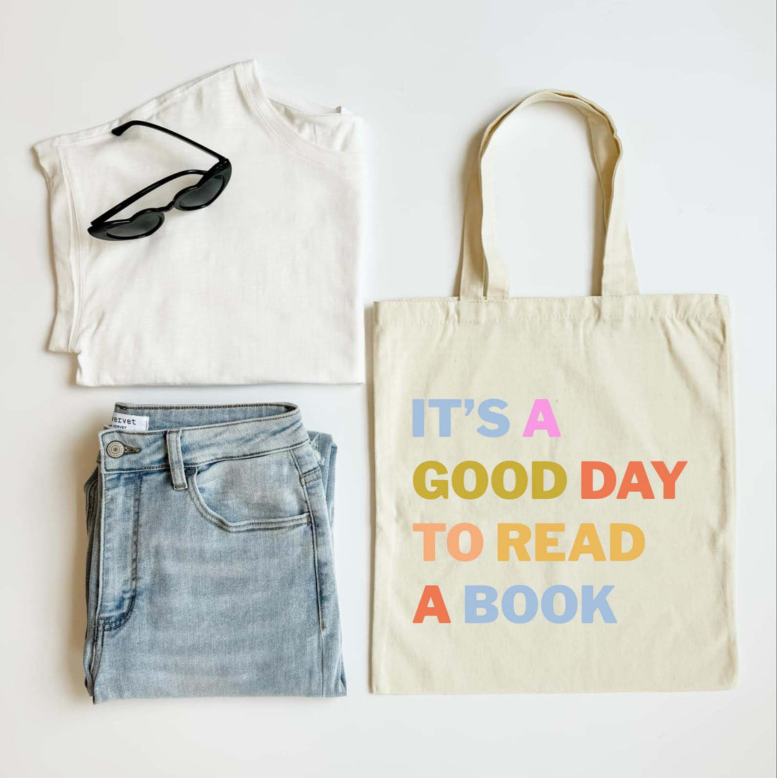 White t-shirt, blue jeans, sunglasses, and a tote bag with text on a white background