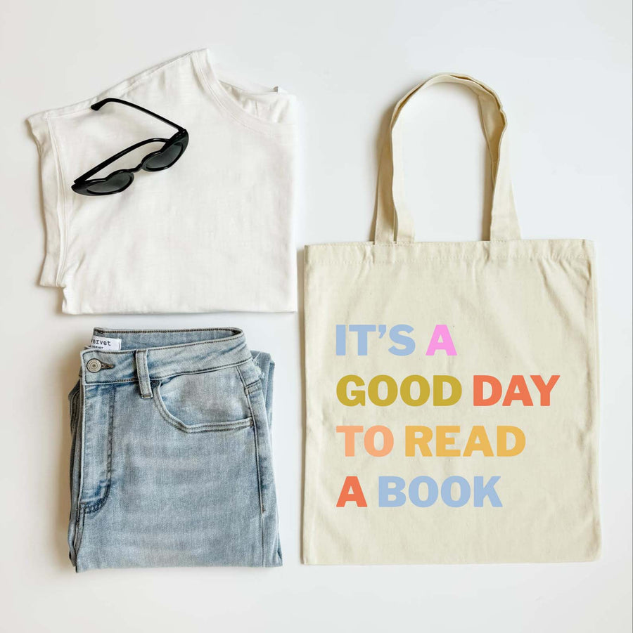 White t-shirt, blue jeans, sunglasses, and a tote bag with text on a white background