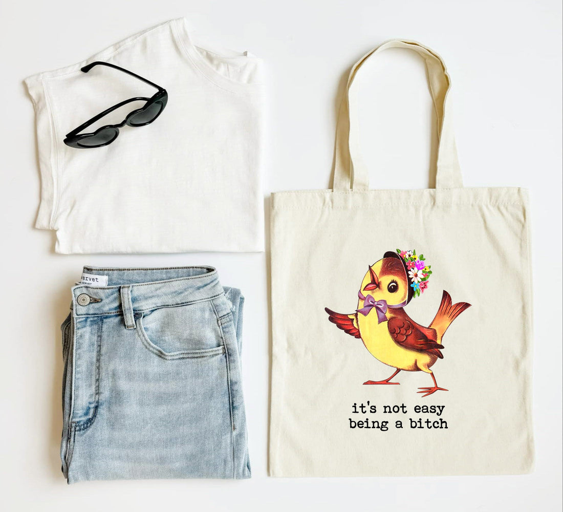 White tank top, blue jeans, black sunglasses, and a tote bag with a colorful bird design on a white background.