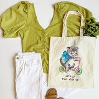 Green top, white pants, and tote bag with a kitten illustration on a white background