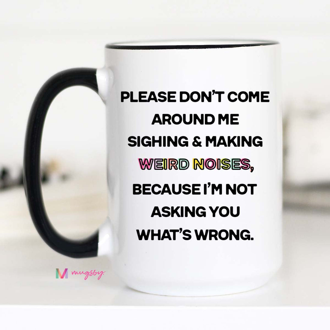 A white ceramic coffee mug with black text and a black handle, featuring the phrase &