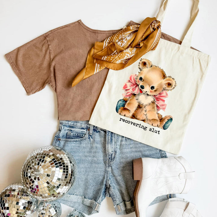 T-shirt, shorts, disco ball, and tote bag with teddy bear graphic on a white background