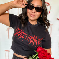 Woman wearing a black t-shirt with red text, holding sunglasses and red roses.