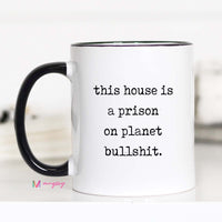 Mug with text 'this house is a prison on planet bullshit' on a white background