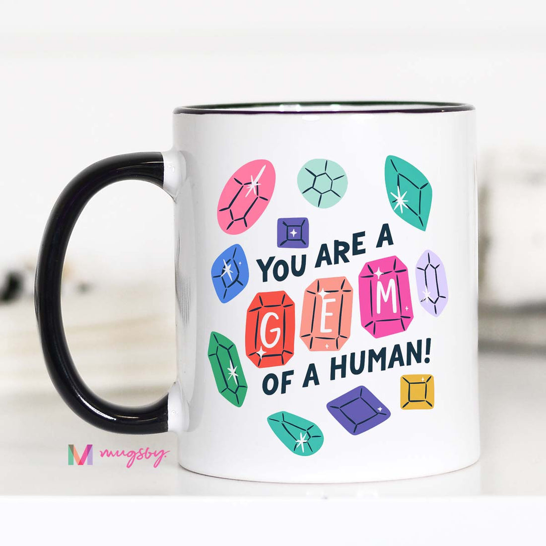 Mug with colorful gemstone designs and text on a white background