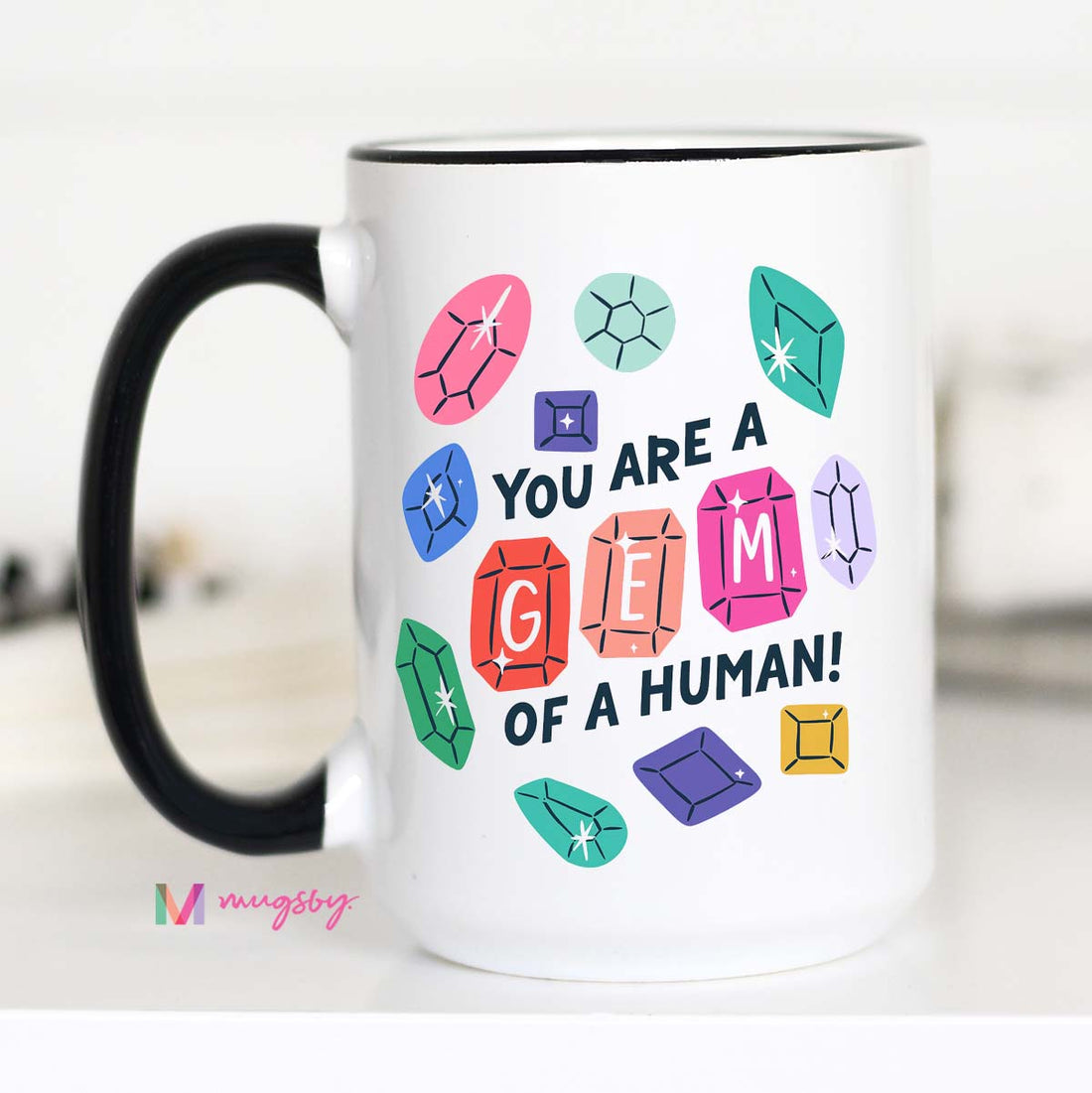 Mug with colorful gem illustrations and text on a white background