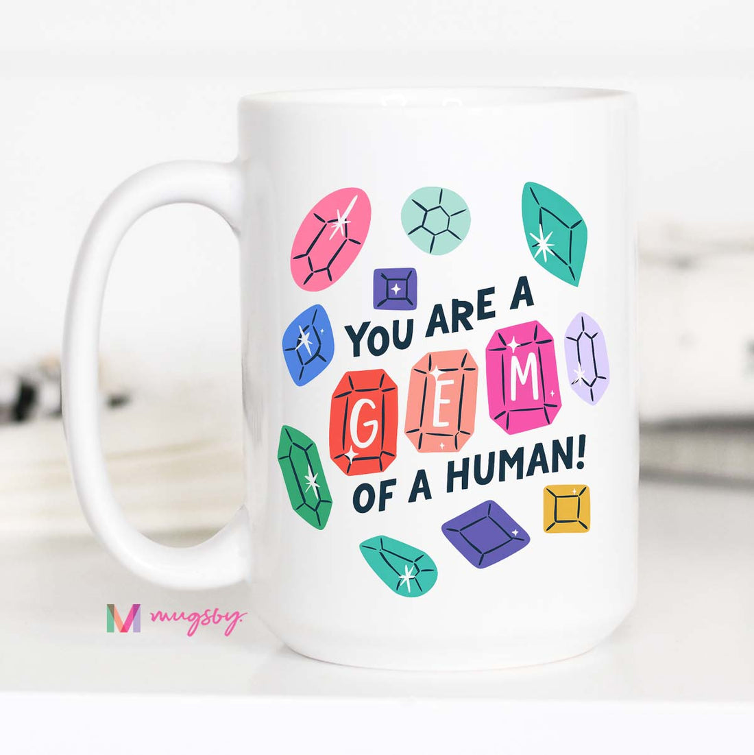 White mug with colorful gem illustrations and text on a white background